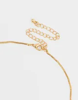 Collar corto dorado con cadena fina y dijes con las letras que forman la palabra 'love' y strass.