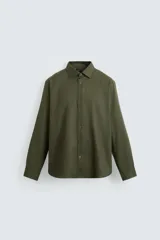 Camisa blanca de corte regular, cuello italiano, manga larga con puños abotonados y cierre frontal con botones.