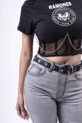 Remera negra de algodón con estampado del logo de la banda de rock Ramones. Presenta un corset de red con cadenas decorativas.