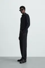 Camisa negra de manga larga con cuello italiano y cierre frontal de botonadura. Presenta un tejido con estructura de fácil cuidado.