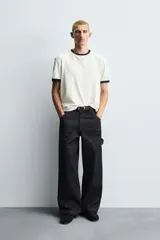 Pantalón de jean negro de corte amplio, con bolsillos delanteros y traseros, presilla portaherramientas en la pierna derecha y costuras a contratono.