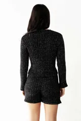 Buzo negro de lurex con tajo delantero y mangas largas.