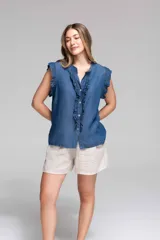 Blusa sin mangas de denim celeste, con volados en el frente y en las mangas, cierre frontal con botones y terminación desflecada.
