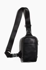 Bolso bandolera negro de cuero sintético con dos compartimentos con cierre, correa ajustable con hebilla y forro interior.