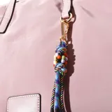 Cartera tipo bandolera en color rosa, con acabado satinado y cierre de cremallera.