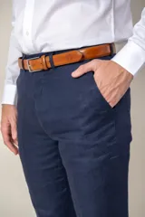 Pantalón de vestir azul marino, de corte recto, confeccionado en lino. Se ajusta a la cintura con cinturón de cuero marrón.