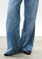 Pantalón de jean celeste de corte wide leg, con diseño de paneles geométricos en las piernas.