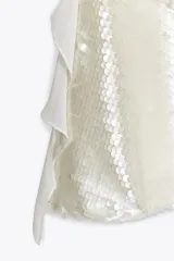 Vestido corto de fiesta color blanco, con lentejuelas y volantes.
