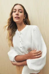 Camisa color crema a rayas verticales finas, de cuello mao, mangas 3/4 abullonadas con elástico en los puños y cierre frontal con botones de nácar.
