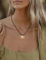 Collar con cordón de cuero negro y dije dorado en forma de hoja.