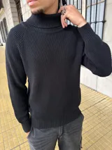 Buzo de hilo negro con cuello alto y mangas largas.