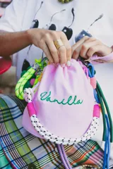 Cartera tipo tote bag color rosa claro, con cordones de colores y bordado verde con la palabra "Vanilla".
