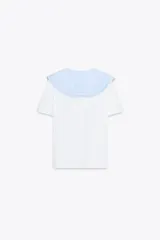Camiseta blanca de manga corta con cuello bobo de tela a cuadros vichy celeste y blanco con bordes bordados. El cuello tiene lazos finos del mismo tejido.
