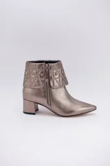 Botas cortas color peltre con taco cuadrado, capellada de cuero y cuello con diseño capitoné y apliques brillantes.