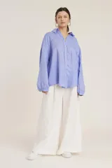 Camisa blanca de manga larga, corte holgado, con cuello camisero y detalles de bordados perforados (calado) verticales en el frente.