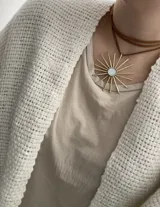Collar con dije en bronce con diseño de sol y nácar en el centro, con tiento marrón de 2 metros de largo.