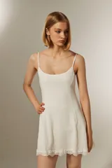 Minivestido blanco de poliéster con textura arrugada, corte al cuerpo, breteles finos, escote cuadrado y terminación de encaje en el ruedo.