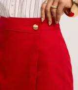 Short pollera de cintura alta confeccionado en sarga color rojo, con traspase sobre y botón diferenciado.