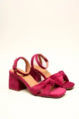 Sandalia de terciopelo verde con taco cuadrado de 7 cm, punta cuadrada y tiras anchas anudadas en el empeine. Cuenta con una tira fina ajustable al tobillo con hebilla dorada.