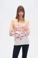 Sweater de tejido de punto, color crema, con estampado floral en tonos rosados y marrones. Presenta cuello redondo y mangas largas.