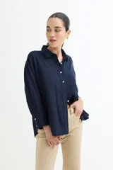 Camisa color beige de corte amplio, con cuello clásico, manga larga y bolsillo en el pecho.