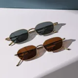Lentes de sol con montura rectangular dorada y lentes marrones y grises.
