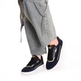 Zapatillas Caterpillar Pause Retro T-Toe de cuero gamuzado negro con detalles dorados y suela blanca.