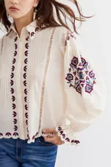 Camisa de calce amplio y caída ligera, confeccionada en algodón con bordados en hilo en el frente y puños elásticos.