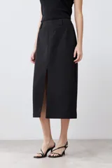 Falda midi negra de corte recto, con tajo lateral y cinturón con hebilla metálica.