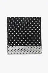 Pañuelo cuadrado con estampado de lunares blancos sobre fondo negro en la mitad superior y lunares negros sobre fondo gris en la mitad inferior.