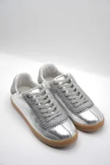 Zapatillas bajas color beige con detalles en marrón y cordones blancos.