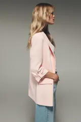 Blazer color marrón oscuro, de corte recto, con cuello solapa y hombreras. Tiene mangas 3/4 con trabilla y botón dorado, y bolsillos delanteros con solapa.
