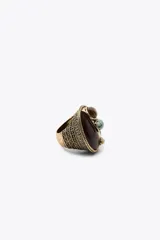 Maxi anillo metálico labrado color dorado con pieza incrustada a color marrón. Detalle aplicación de piedras combinadas a contraste en marrón, verde y beige.