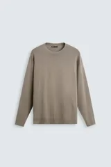 Jersey color topo de corte amplio, tejido en hilatura con mezcla de viscosa. Tiene cuello redondo, manga larga y terminaciones en rib.