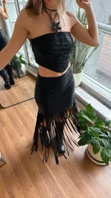 Minifalda negra con flecos largos en el ruedo.