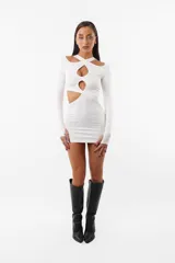 Vestido corto blanco de microfibra, ajustado al cuerpo, con aberturas en el frente y en los laterales. Tiene mangas largas con mitones en los pulgares y elástico interno en las terminaciones.