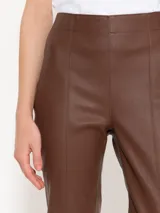 Pantalón de cuero marrón con corte ajustado y aberturas en el ruedo.