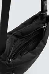 Bandolera negra de tejido técnico con compartimento principal con cierre de doble cremallera, bolsillo interior con cremallera y bolsillo frontal con cremallera. Tiene asa de hombro ajustable.