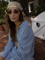 Camisa a rayas beige y blanco, de corte holgado, con cuello camisero y mangas largas fruncidas con lazos.