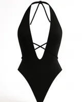 Body negro con escote halter profundo y espalda descubierta. Presenta tiras cruzadas en el frente y corte cavado.