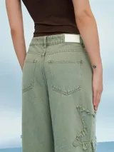 Pantalón jean de tiro alto color verde oliva, corte acampanado y detalles rotos con flecos.