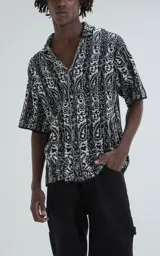 Camisa de manga corta, tejida de punto abierto (símil crochet), con estampado paisley en blanco y negro, y calce oversize.