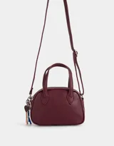 Cartera bowling color gris claro de cuerina con doble asa corta de mano, correa regulable y cierre superior.