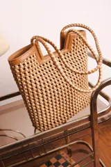 Bolso tipo tote de cuero color tostado, con diseño trenzado a mano.