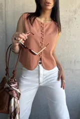 Chaleco color terracota con botones frontales y corte irregular en el ruedo. Sin mangas y con cuello redondo.