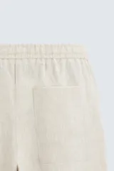 Pantalón de lino color marrón oscuro, de corte recto y relaxed fit. Tiene cintura elástica ajustable con cordón, bolsillos frontales y traseros de parche.