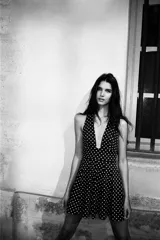 Vestido corto negro con lunares blancos, cuello halter y escote pico. Detalle de lazo en la espalda y cierre lateral con cremallera oculta.