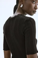 Top negro de punto acanalado con corte holgado, cuello redondo y mangas cortas con ribete sobrehilado.