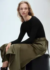 Vestido midi evasé color verde oliva, con efecto satinado, cuello barco, manga larga, cinturón decorativo y cierre lateral con cremallera.