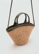 Bolso pequeño de mano tejido con fibras naturales color beige y detalles en cuero sintético verde oscuro. Tiene doble asa corta, correa larga al hombro y cierre con botón magnético.